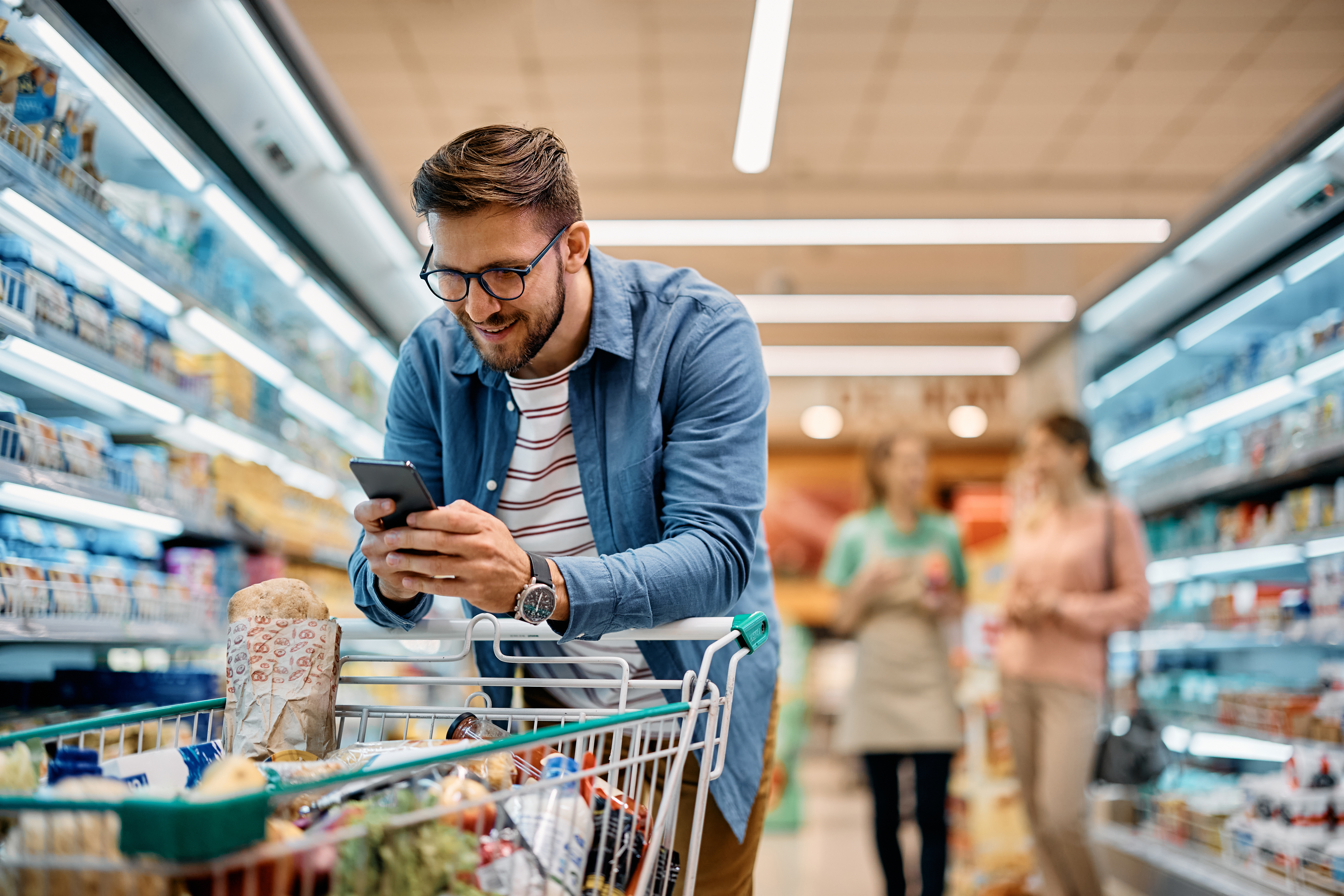 Homem com celular no supermercado